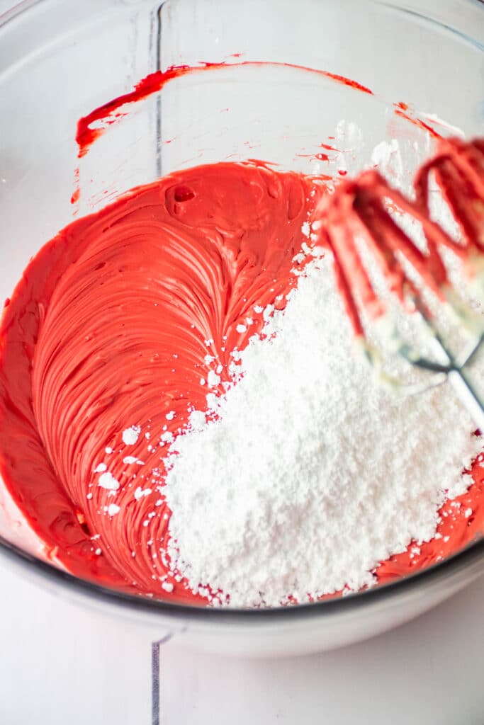 red velvet cheesecake batter in a glass mixing bowl with powdered sugar