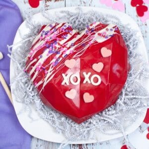 square image of red smashable heart on a white plate with a purple napkin