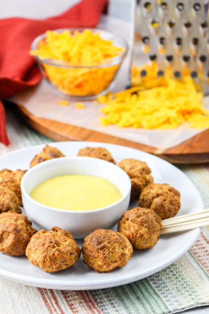 off center image of a plate of air fryer sausage balls with a small bowl of honey mustard in bowl