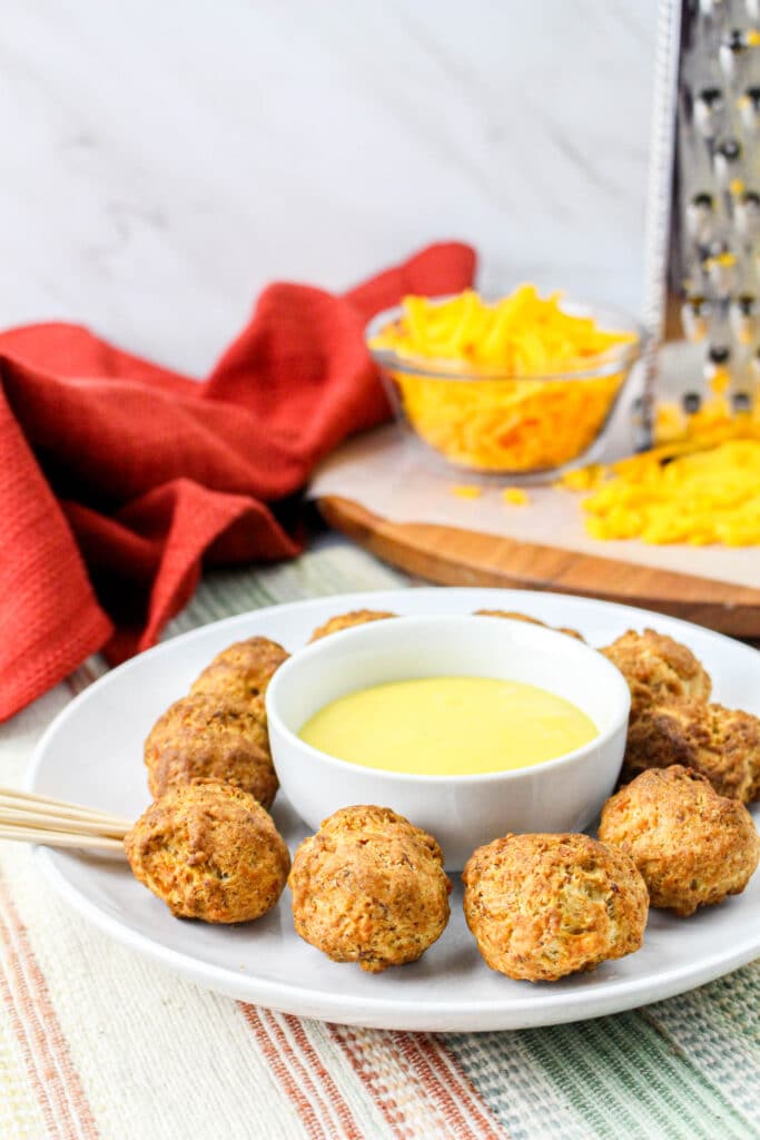 Air Fryer Sausage Balls on a white plate surrounding a bowl of honey mustard sauce