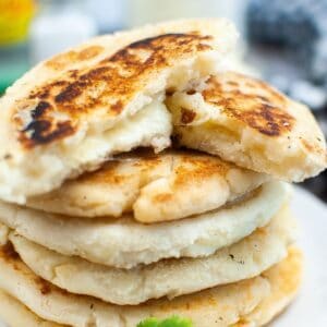 close up image sized for the recipe card on arepas con queso with the top one broken open