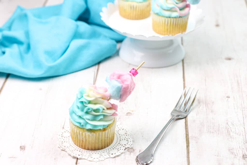 single cotton candy cupcake on a lace with a wooden background