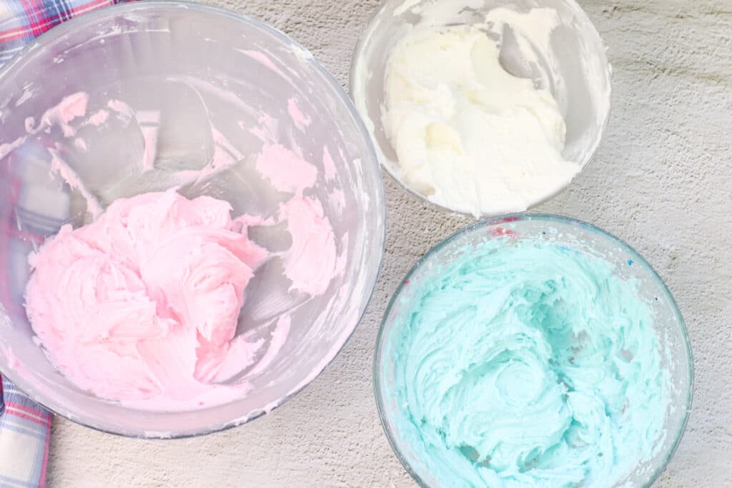 pink, blue and white frosting in bowls