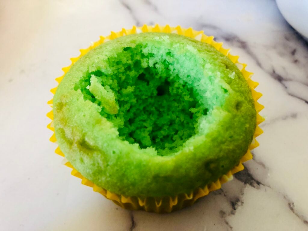 green cupcake with the center ripped out on a marble countertop