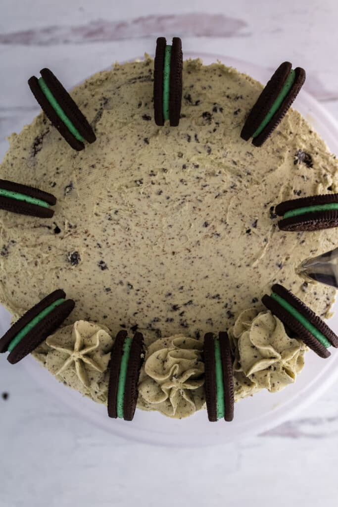 Mint Oreo Cake being topped with Mint Oreo Cookies