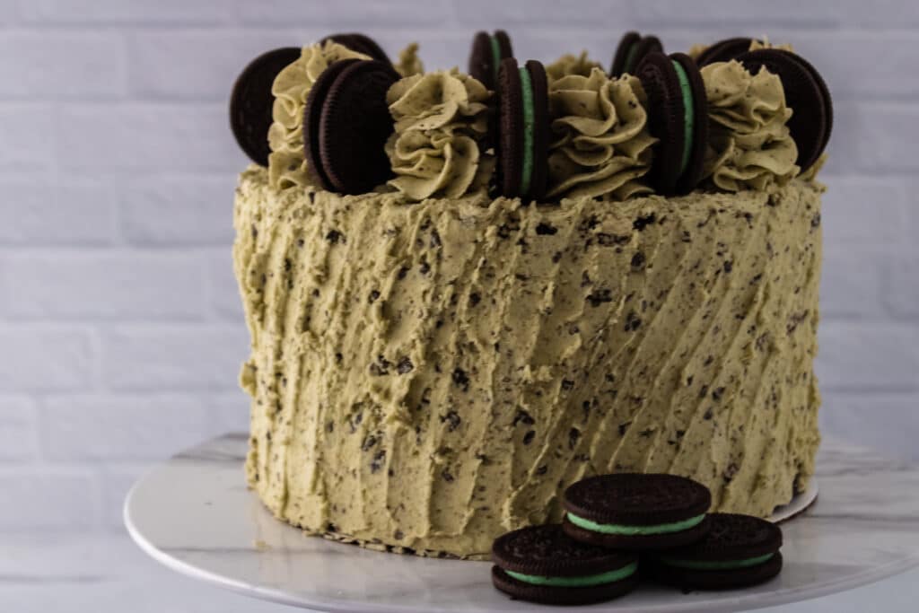 Off center shot of a whole Oreo Mint Cake with three Mint Oreo Cookies on a cake plate