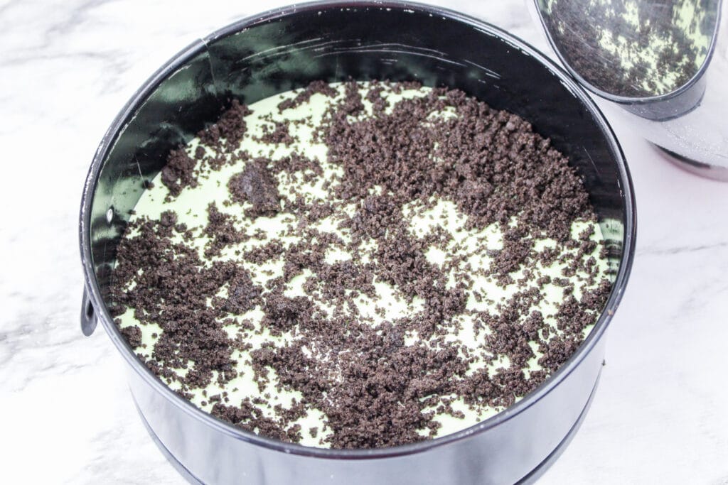 half of the cheesecake batter in a springform pan with crushed oreos on top