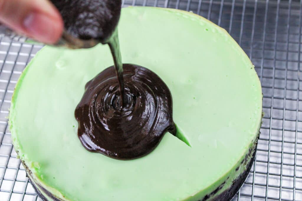 mint cheesecake with chocolate ganache being poured over top