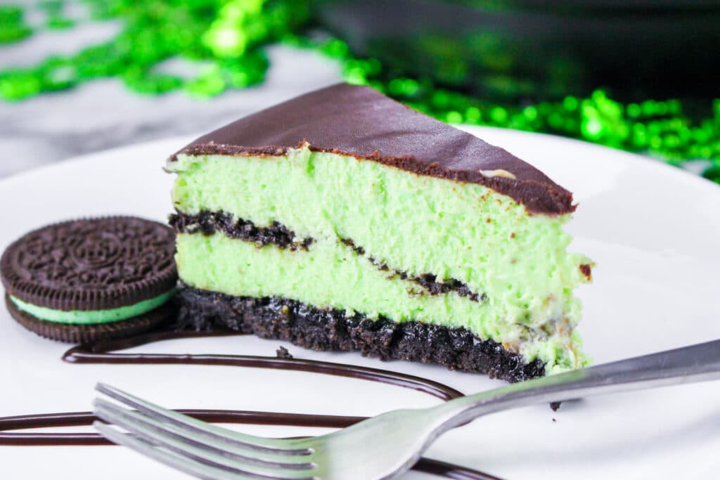 close up a slice of instant pot mint cheesecake on a white plate with a sliver fork