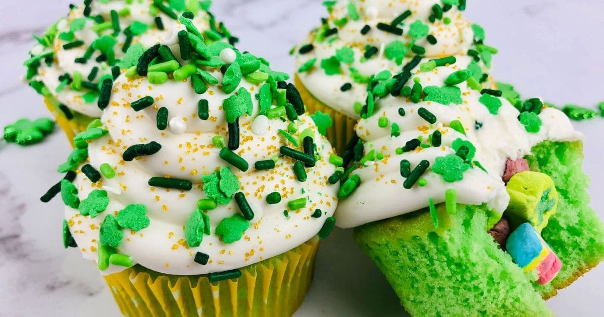 close up rectangle image of four lucky charms cupcakes on white marble counter