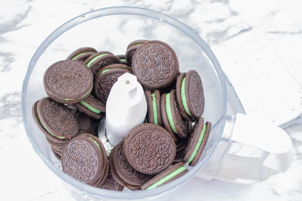 mint oreos in a food processor on a marble counter