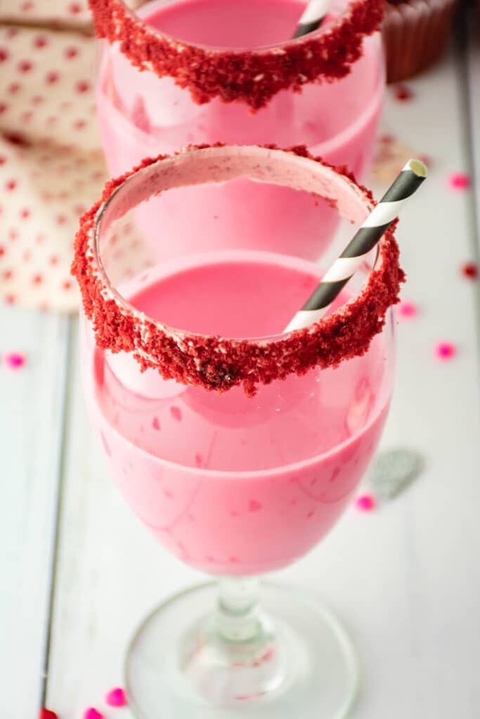 top view of a glass of red velvet cocktail with a black and white stripped strawberry