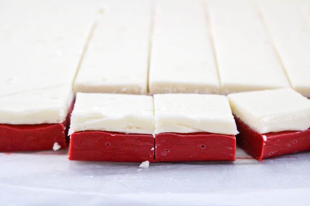 finished red velvet fudge being cut into squares on a baking sheet