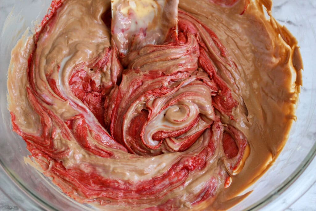 red velvet fudge being mixed in a glass mixing bowl