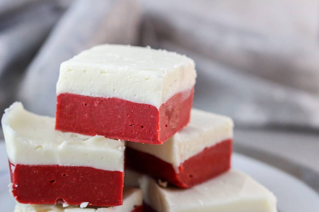 close up image of three pieces of red velvet fudge with a cream cheese top layer