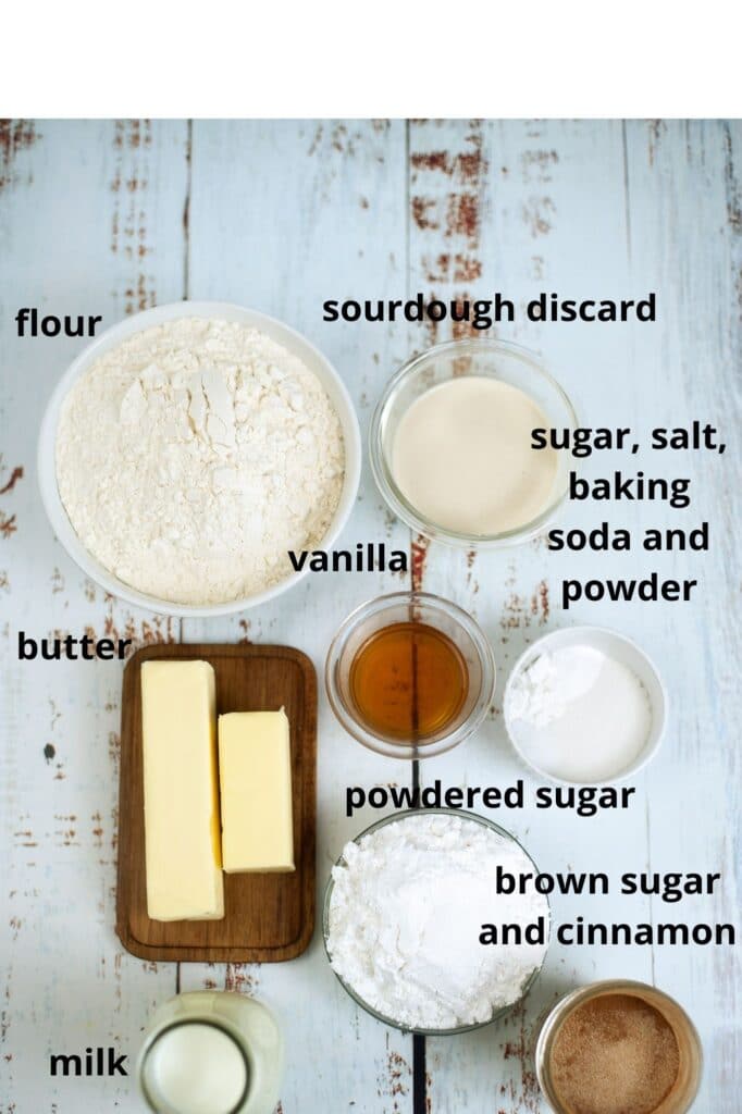 ingredients for sourdough discard cinnamon rolls on a wooden background labelled with text
