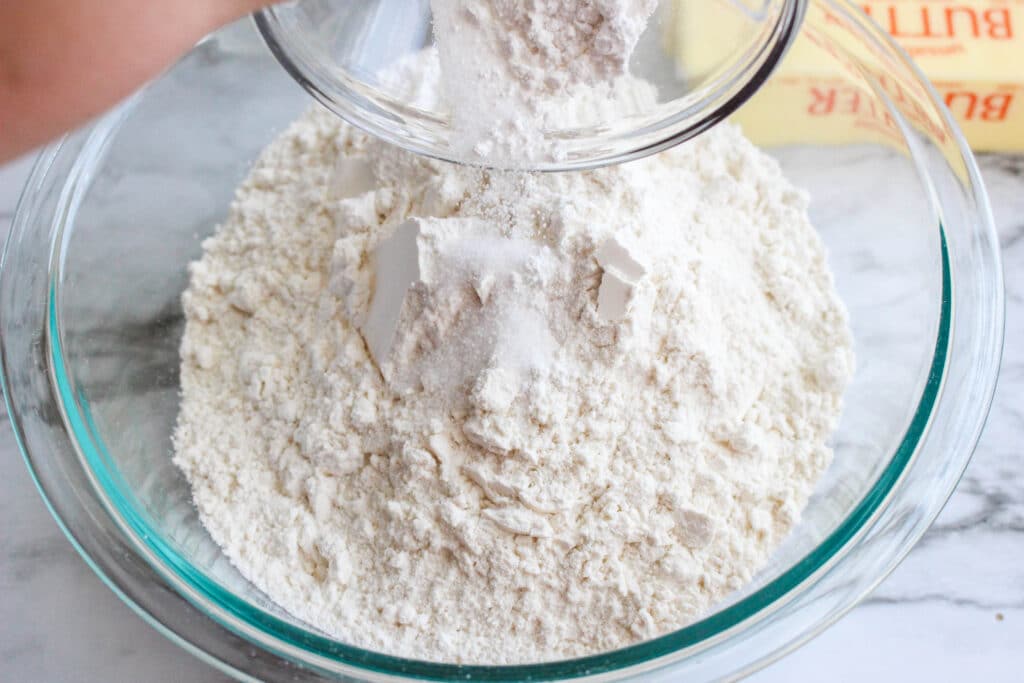 flour and sugar in a glass mixing bowl on a marble counter