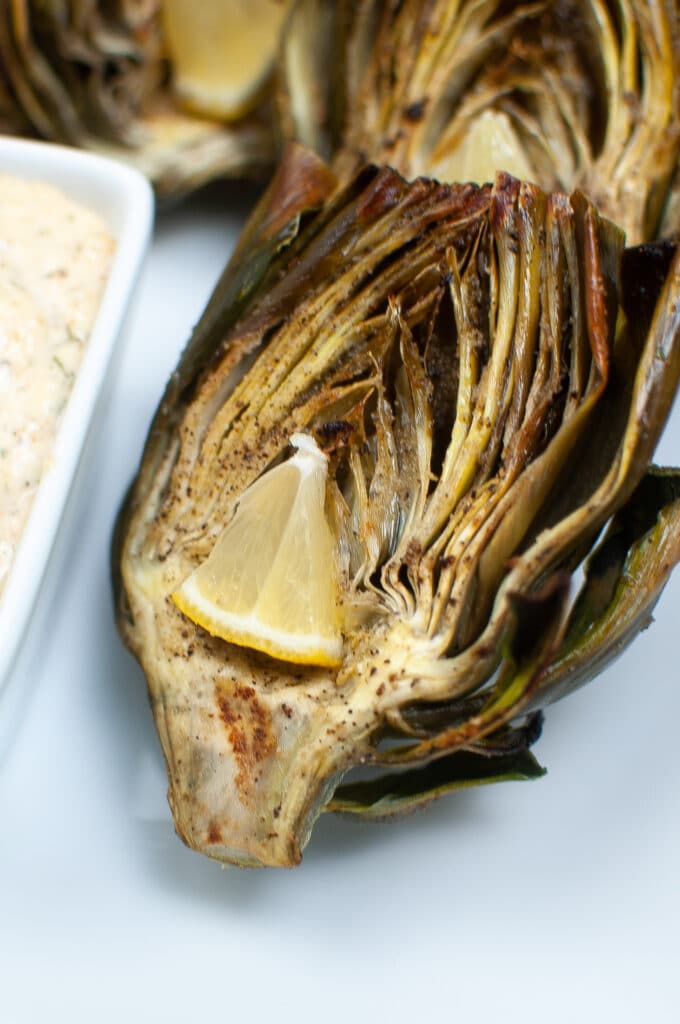 close up image of an air fryer artichoke on a white plate