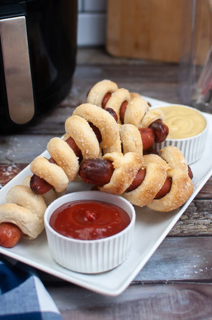 Air Fryer Pretzel Dogs on a white plate with a small bowl with ketchup