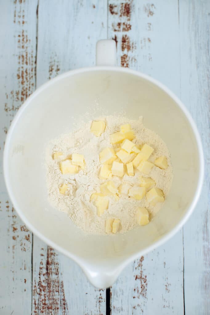 cubed butter and flour in a white mixing bowl on a wooden background