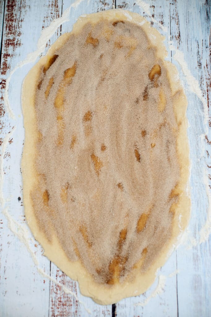 dough topped with brown sugar and cinnamon on a wooden background