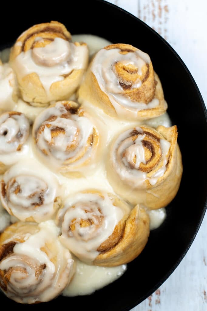 cinnamon rolls in a cast-iron skillet topped with a simple glaze
