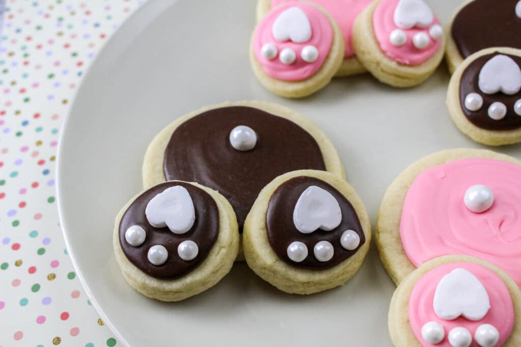 four bunny butt cookies on a white plate off center