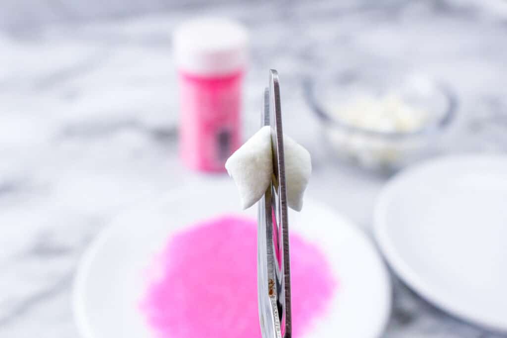close up of a mini marshmallow being cut in half with scissors