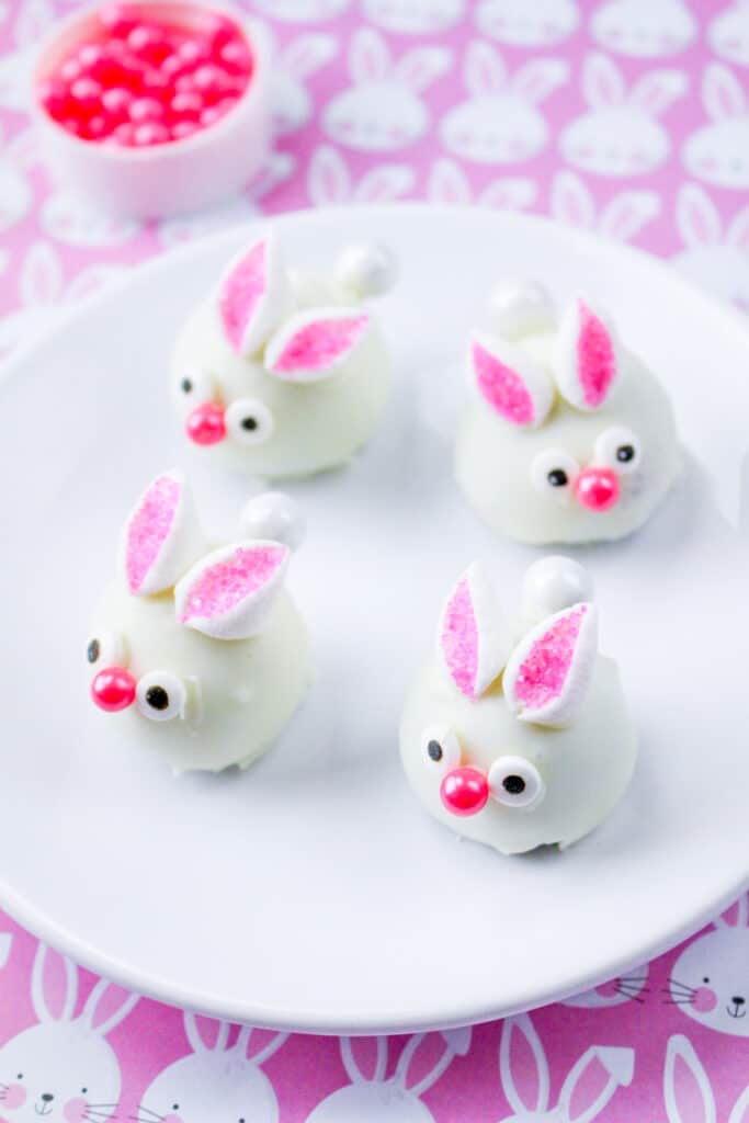 close up of bunny oreo truffles on a white plate with a purple tablecloth with bunnies on it