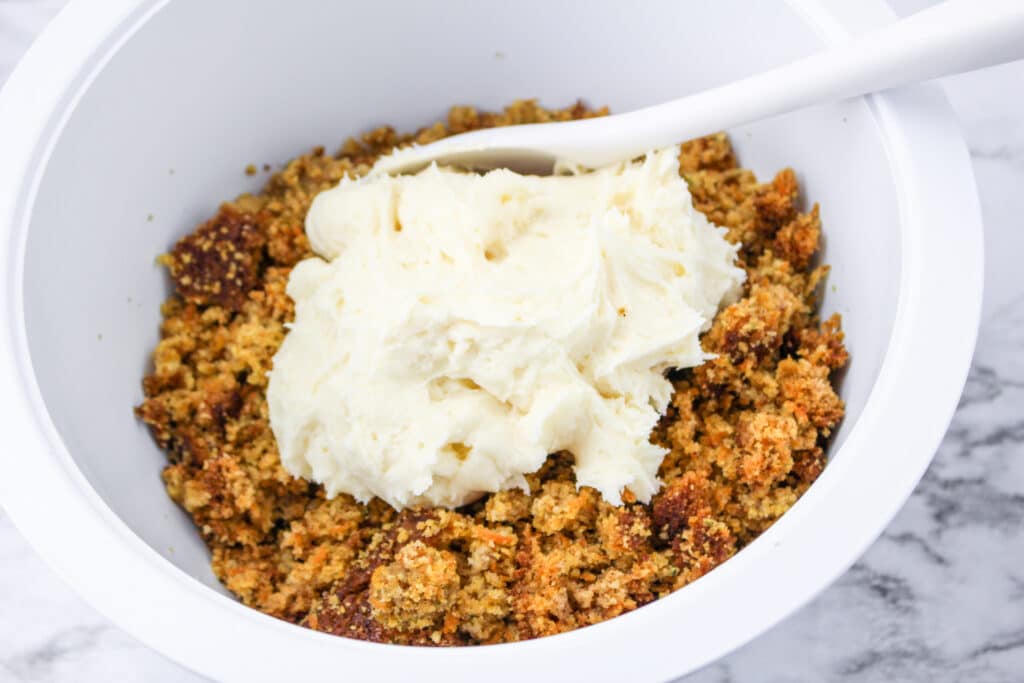 carrot cake crumbles and cream cheese frosting in a white plate