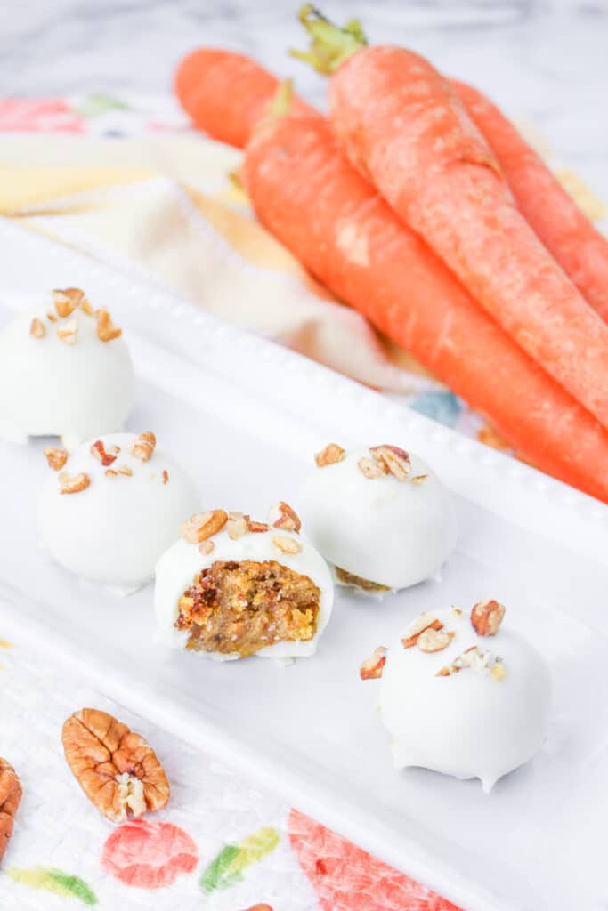 carrot cake truffles on a white plate with one bitten in half