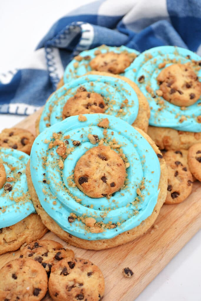 five Blue Monster Cookies laying on a wooden cutting board