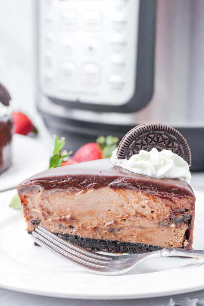 slice of oreo nutella cheesecake on a white plate with the instant pot in the background