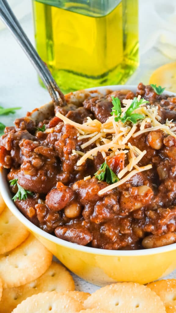 close up of a yellow bowl filled with smoked chili and topped with cheddar cheese