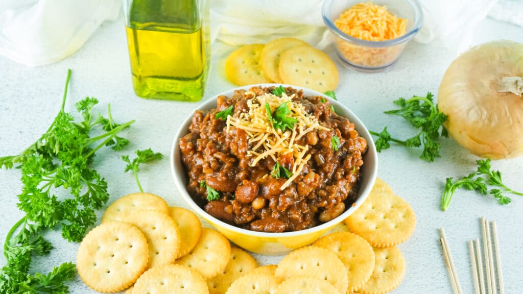 yellow bowl filled with smoked chili with ritz crackers around it