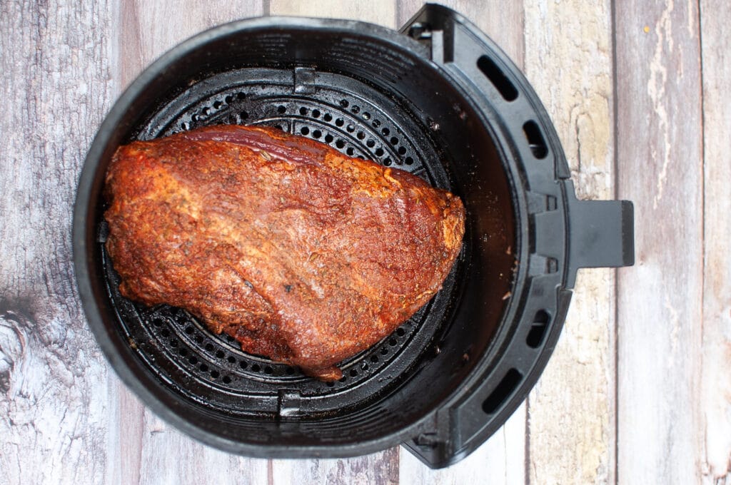 cooked tri tip in an air fryer basket on a wooden background