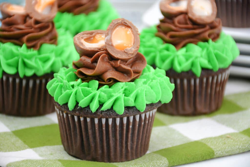 chocolate cupcake topped with green frosting and open cadbury mini egg