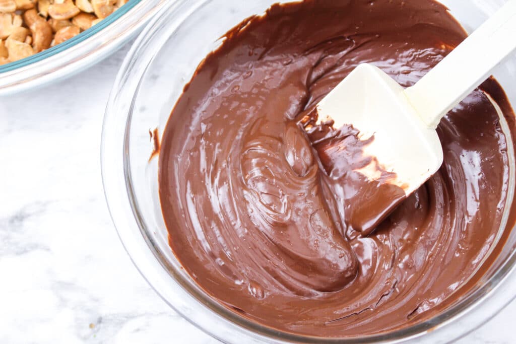 melted chocolate in a glass mixing bowl with a rubber spatula