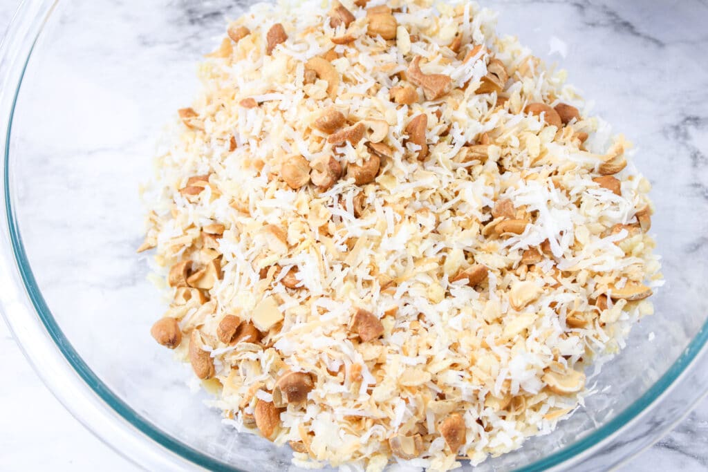 toasted coconut, cashews and rice cereal in a glass mixing bowl