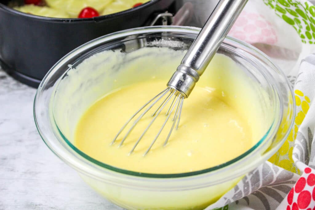 vanilla cake batter in a glass mixing bowl with a whisk