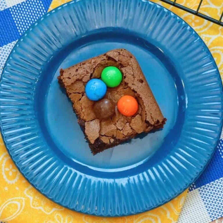 single m&m brownie on a blue plate with flouted ridges