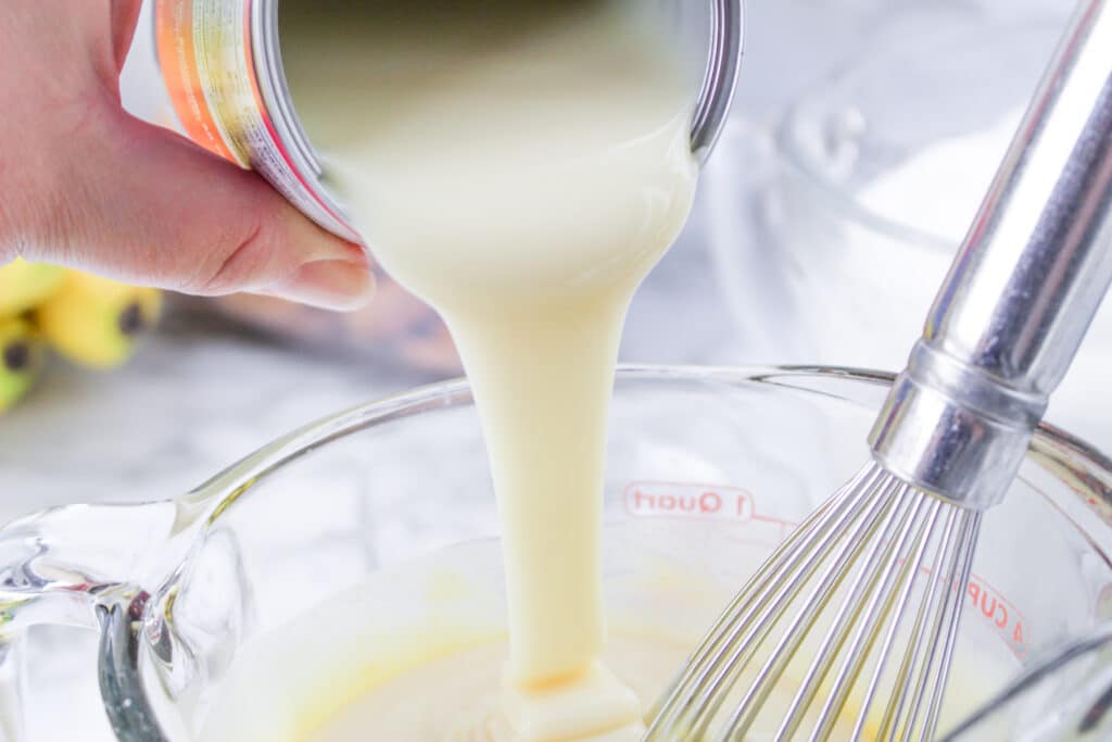 condensed milk being poured into a mixing bowl