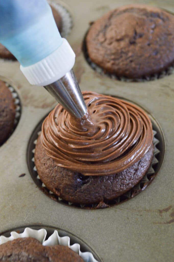 chocolate cupcake being frosted with chocolate frosting