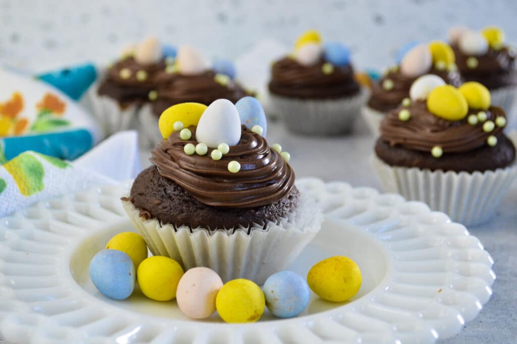 horizontal image of chocolate mini egg cupcakes on a white plate