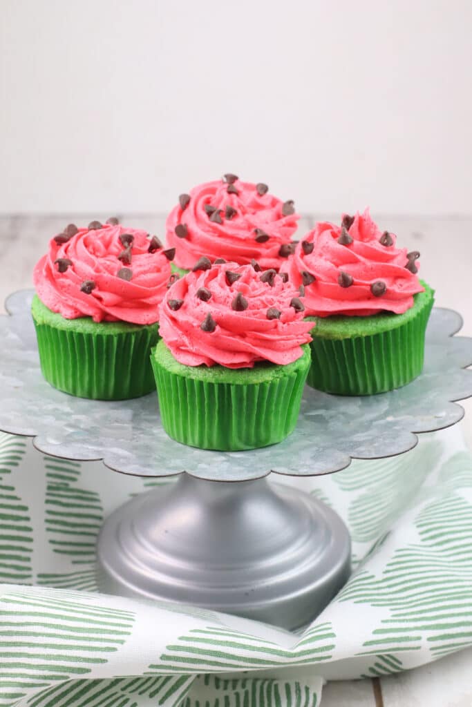 four watermelon cupcakes on a stainless steel cake stand