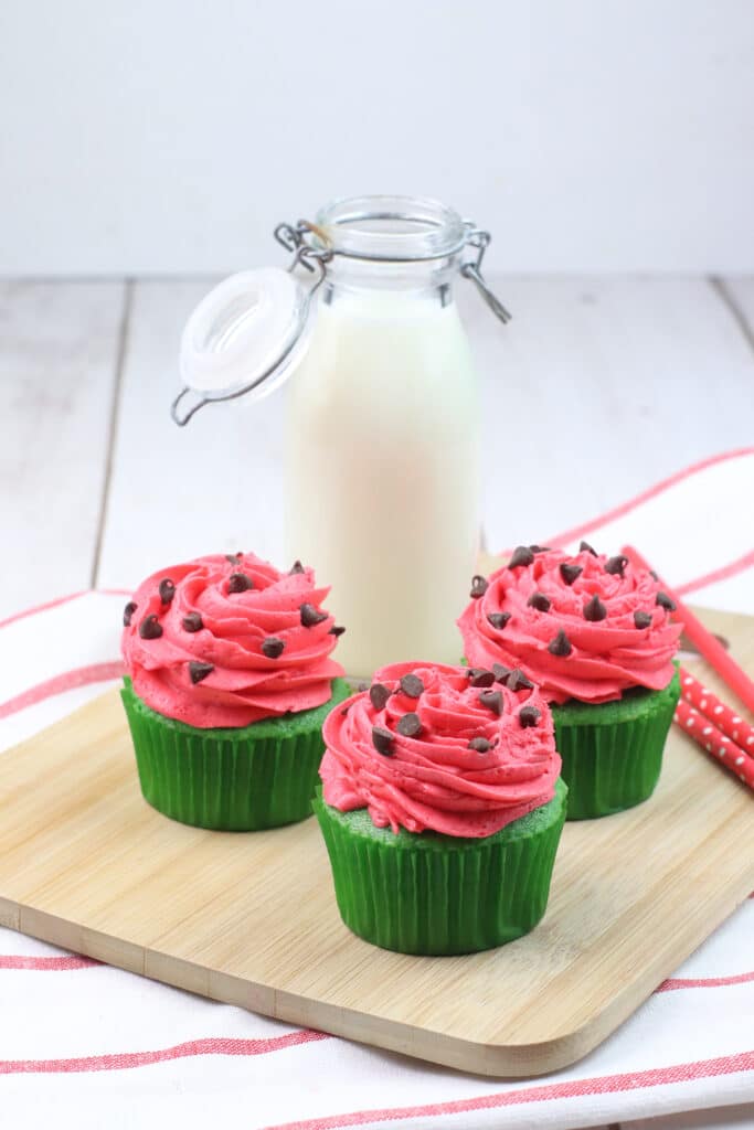 three watermelon cupcakes on a wooden cutting board