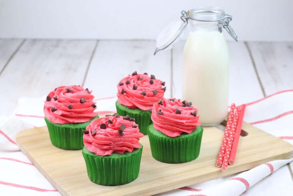 four watermelon cupcakes on a wooden cutting board