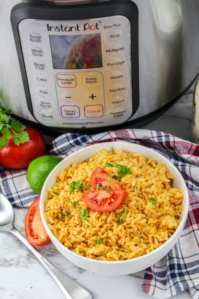 white bowl filled with instant pot mexican rice with the pressure cooker in the background