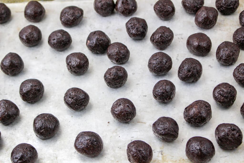 shaped undipped oreo balls on a parchment lined baking sheet