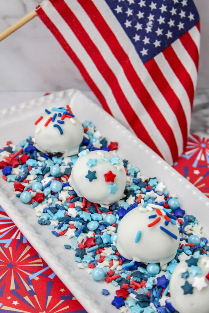 Patriotic Oreo Balls on a white platter with sprinkles